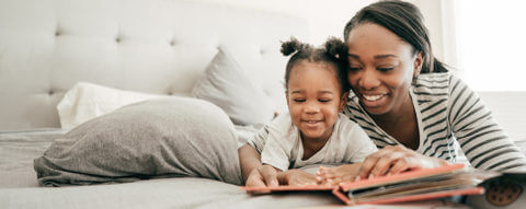 Close-up of mom and daughter reading on bed